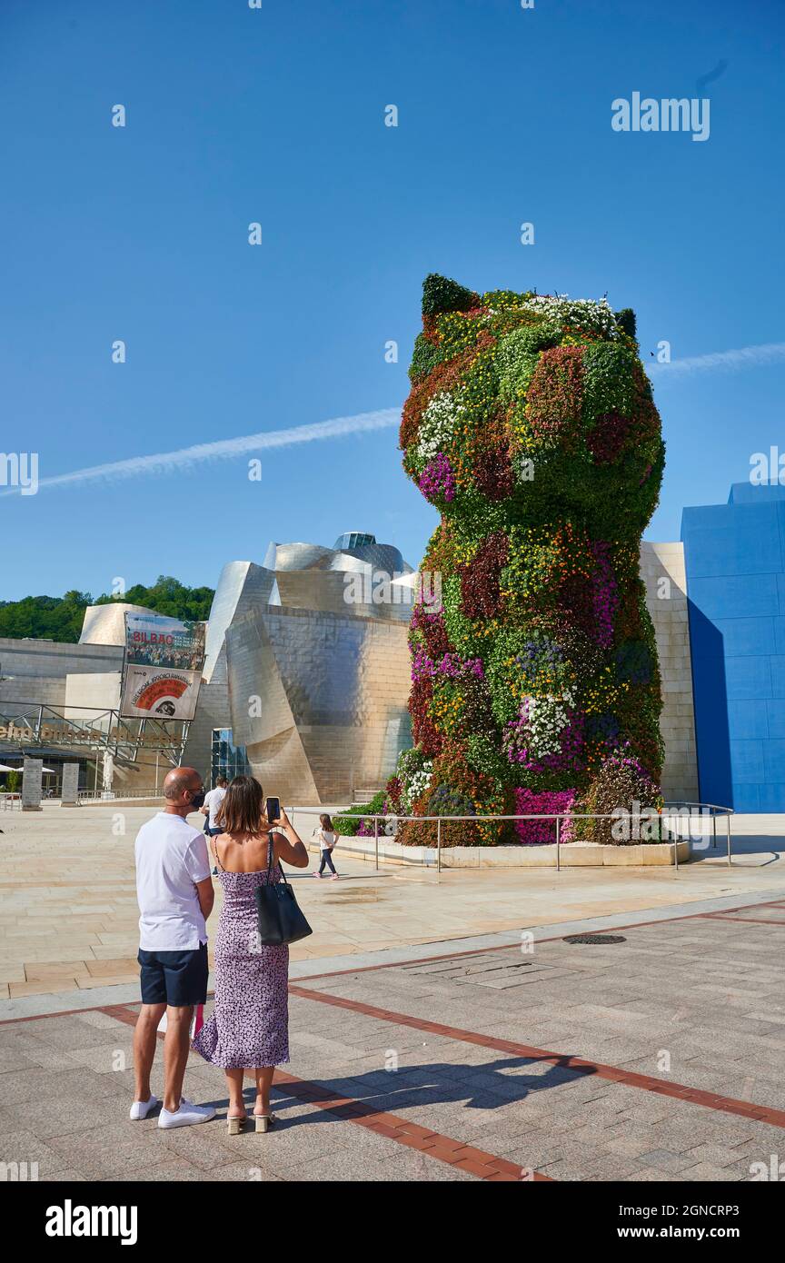 Couple of tourist looking to the 'Puppy' the famous sculpture by Jeff Koons in the outdoors of the Guggenheim museum, Bilbao, Biscay, Basque Country Stock Photo