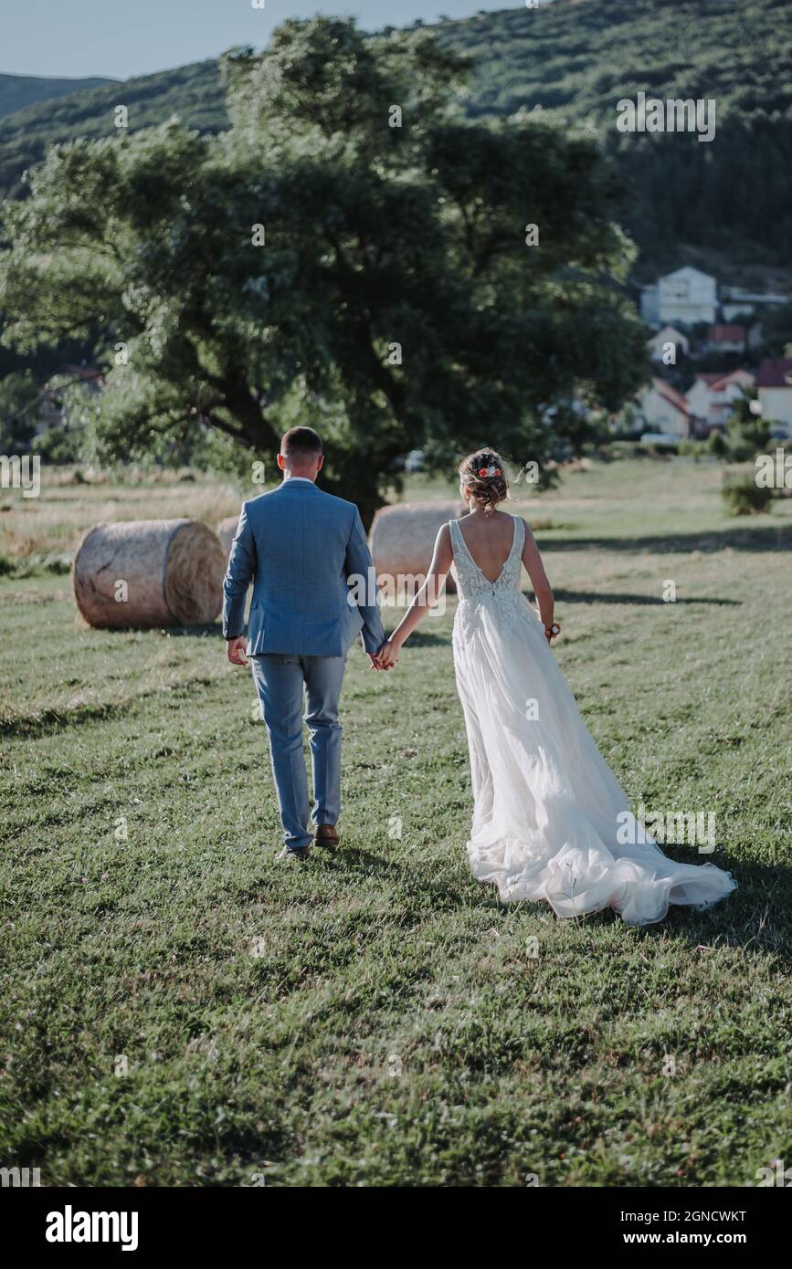 Serene View Of The Beautiful Bride And Groom Walking In The Field In serene-view-of-the-beautiful-bride-and-groom-walking-in-the-field-in