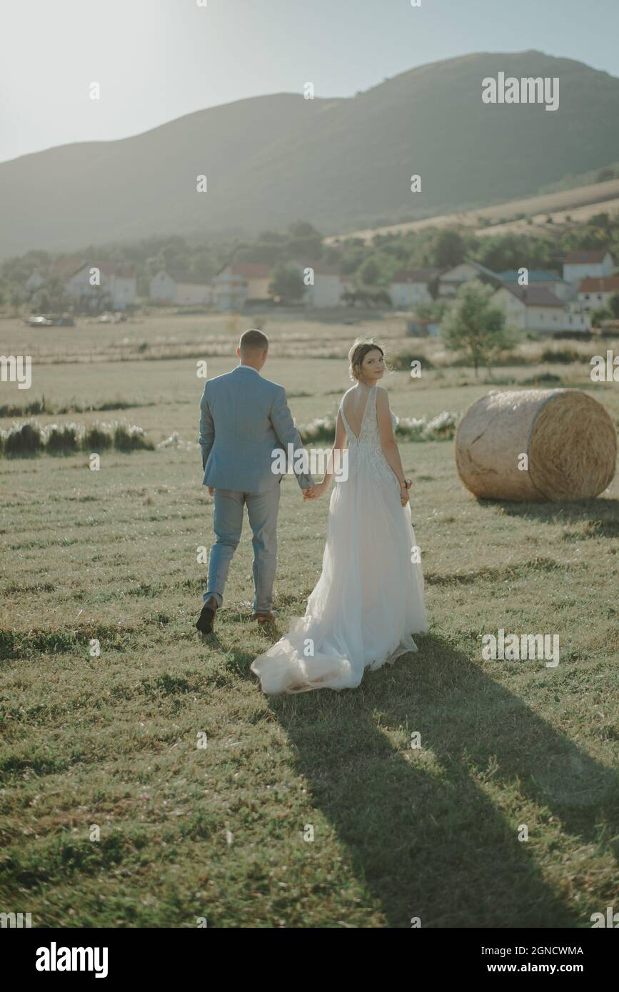 Serene View Of The Beautiful Bride And Groom Walking In The Field In serene-view-of-the-beautiful-bride-and-groom-walking-in-the-field-in