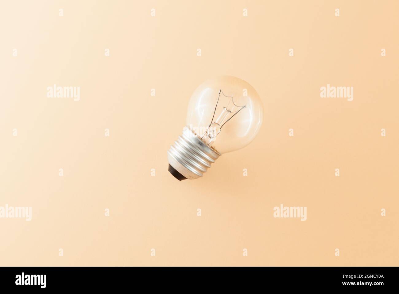 Top view of a round tungsten filament bulb isolated on a beige background. Stock Photo