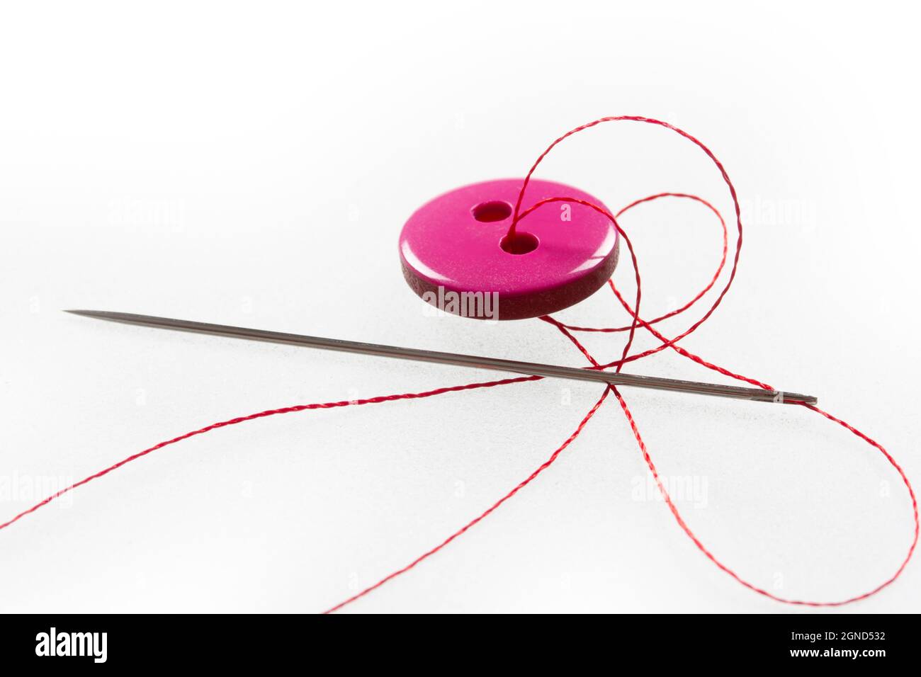 two thread holes, pink button, needle and thread Stock Photo