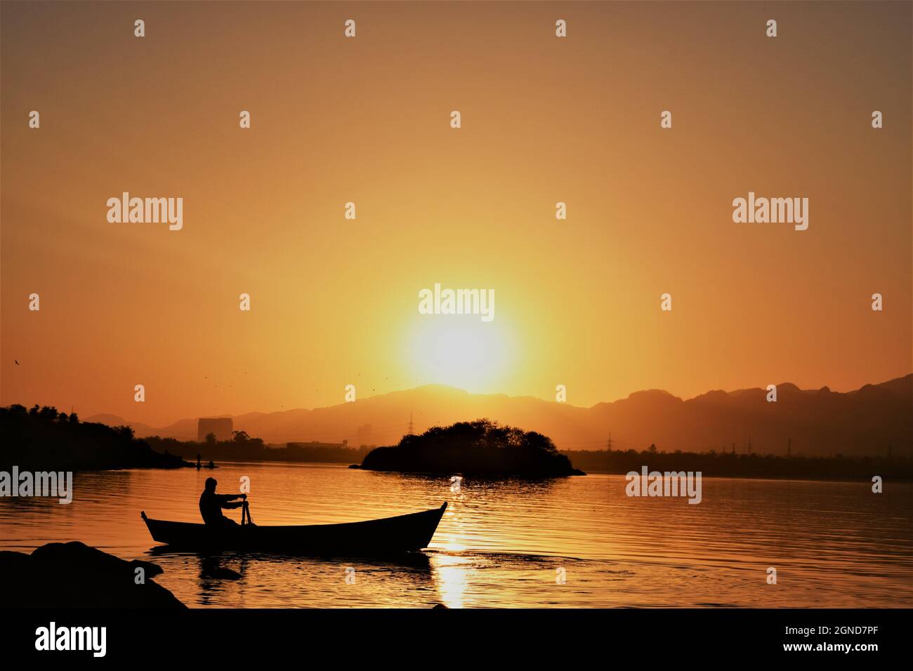 Silhouette of a fisherman riding a boat on the water during a beautiful ...