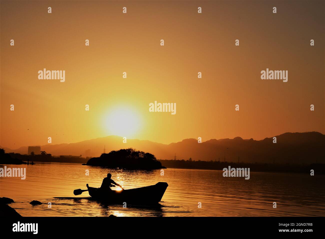 Silhouette of a fisherman riding a boat on the water during a beautiful ...