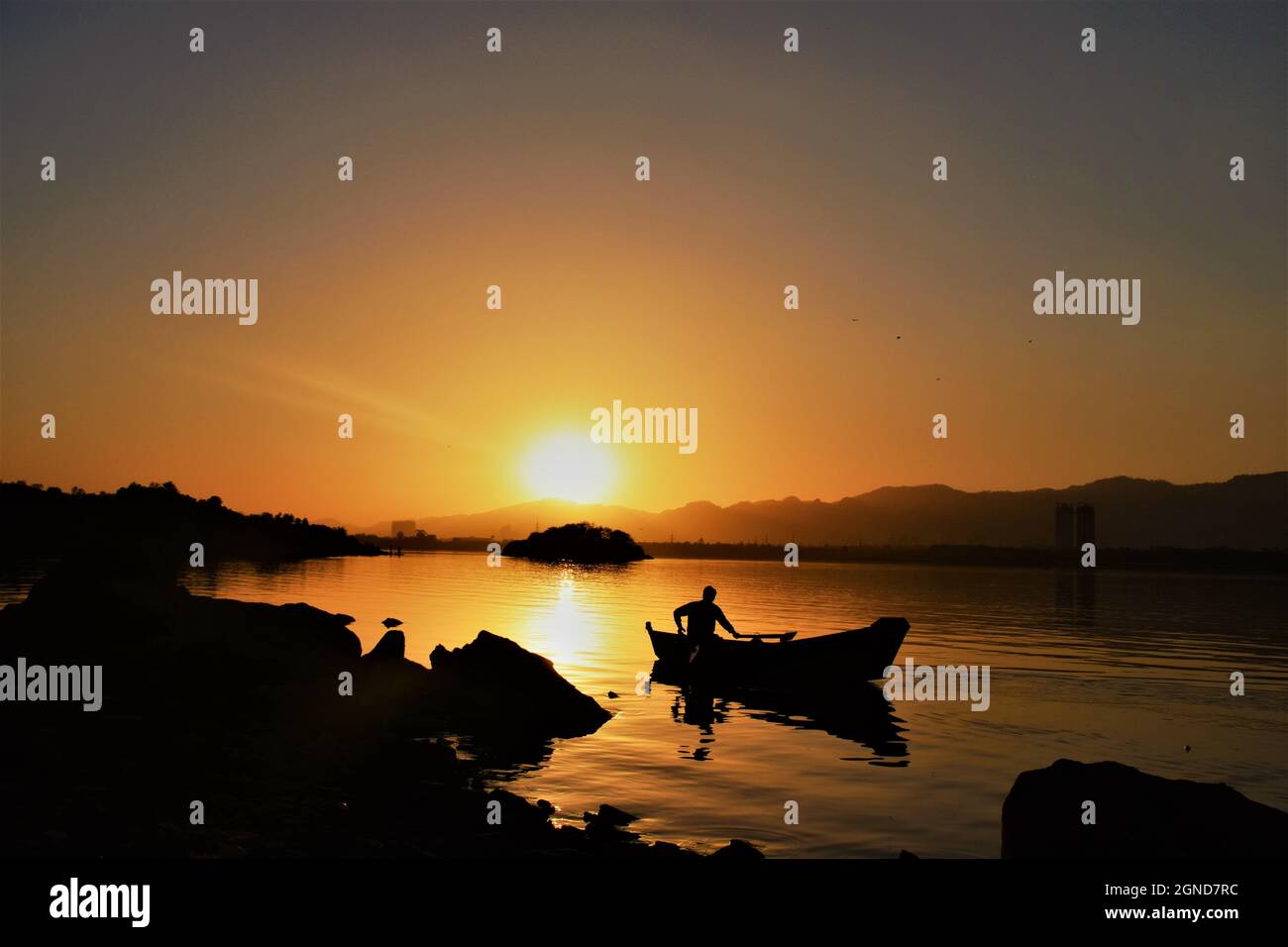 Silhouette of a fisherman on a boat on the water during a beautiful ...