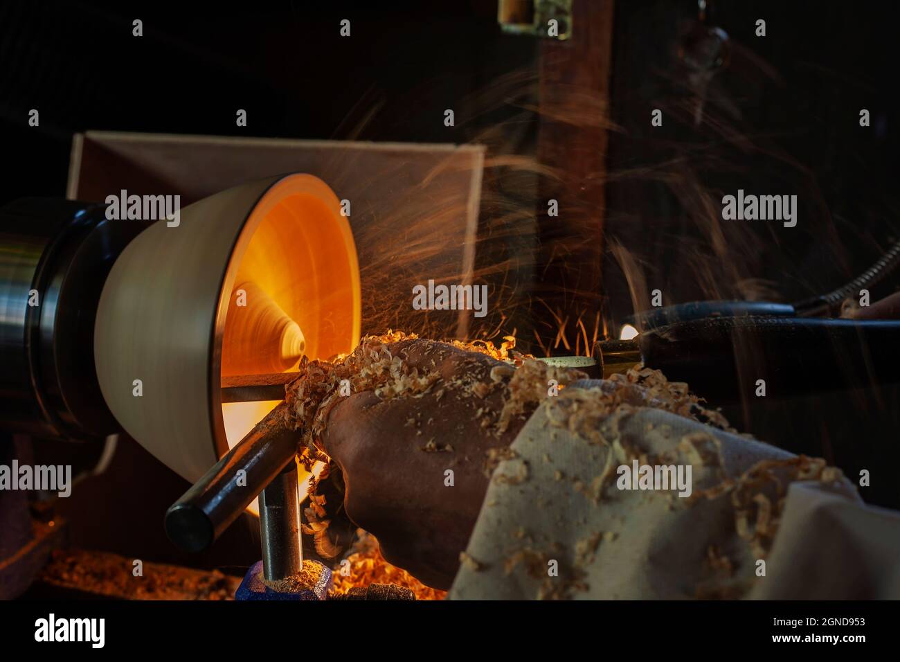 A wooden bowl being turned by a man on a woodturning lathe.A craftsman at work.Sawdust is flying. Stock Photo