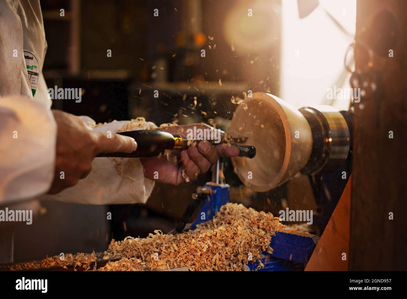 A wooden bowl being turned by a man on a woodturning lathe.A craftsman at work.Sawdust is flying. Stock Photo