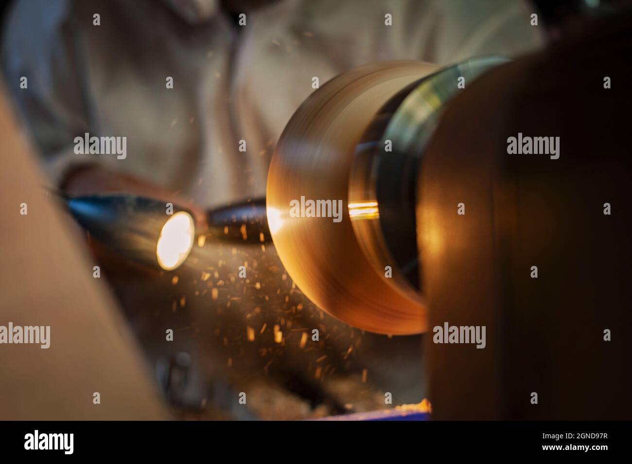 A wooden bowl being turned by a man on a woodturning lathe.A craftsman at work.Sawdust is flying. Stock Photo