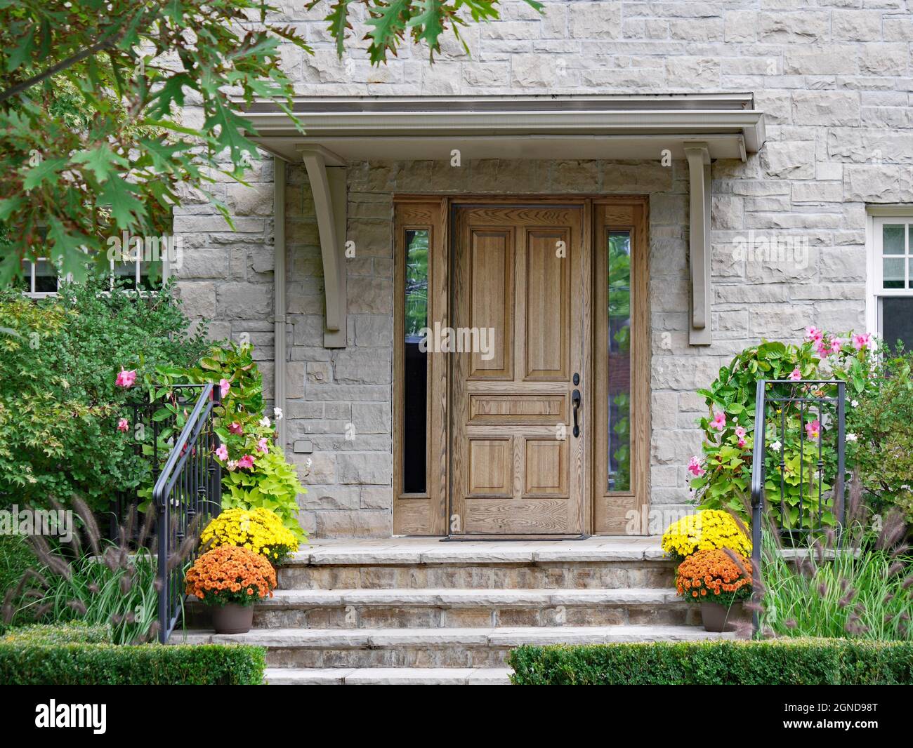Front steps of stone house with wood grain front door and flower pots ...