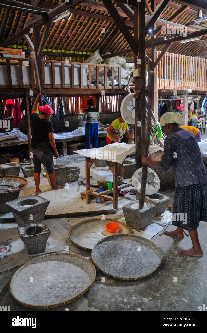 The atmosphere where rice flour is made in a traditional cake factory, women grinding rice into flour with a stone mortar and pestle made of wood. Stock Photo