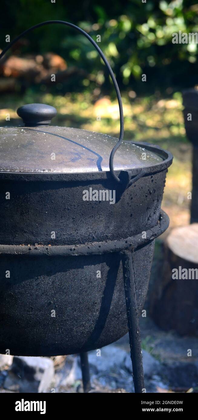 black iron pot, kettle closed with soot in nature in the woods Stock Photo