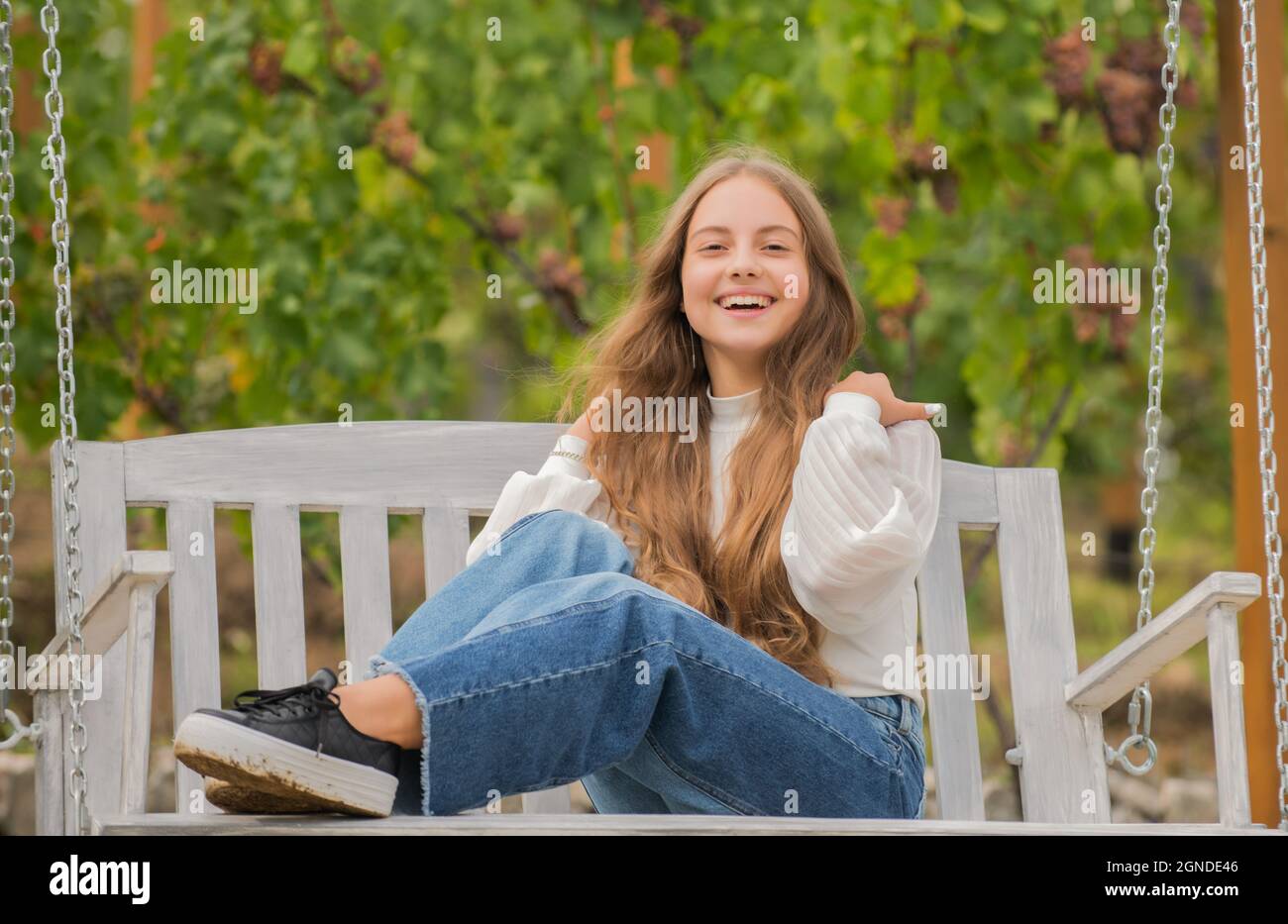 glad teen girl having free time outside on swing, playground Stock Photo