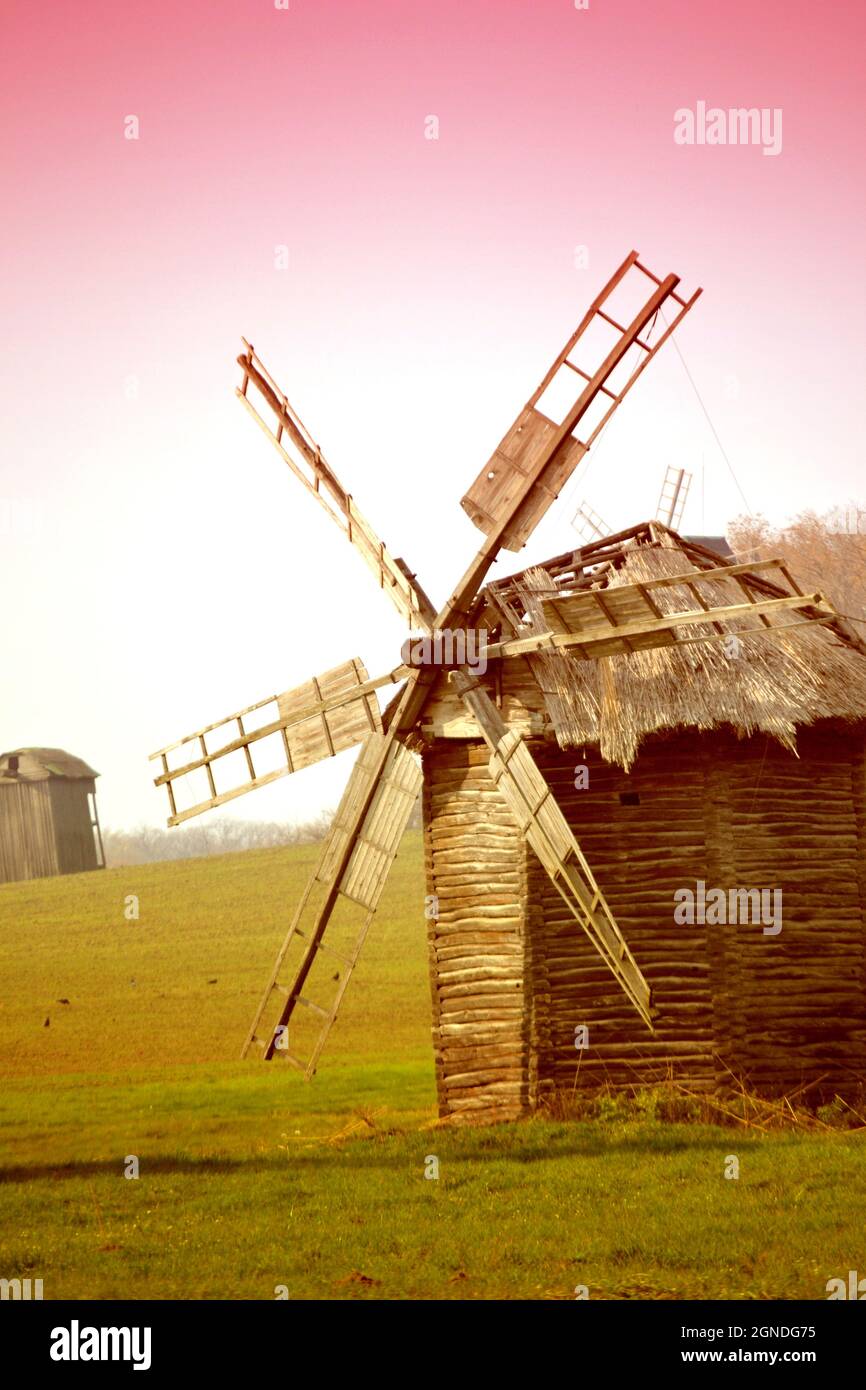 ancient windmill on the field with pink filter Stock Photo