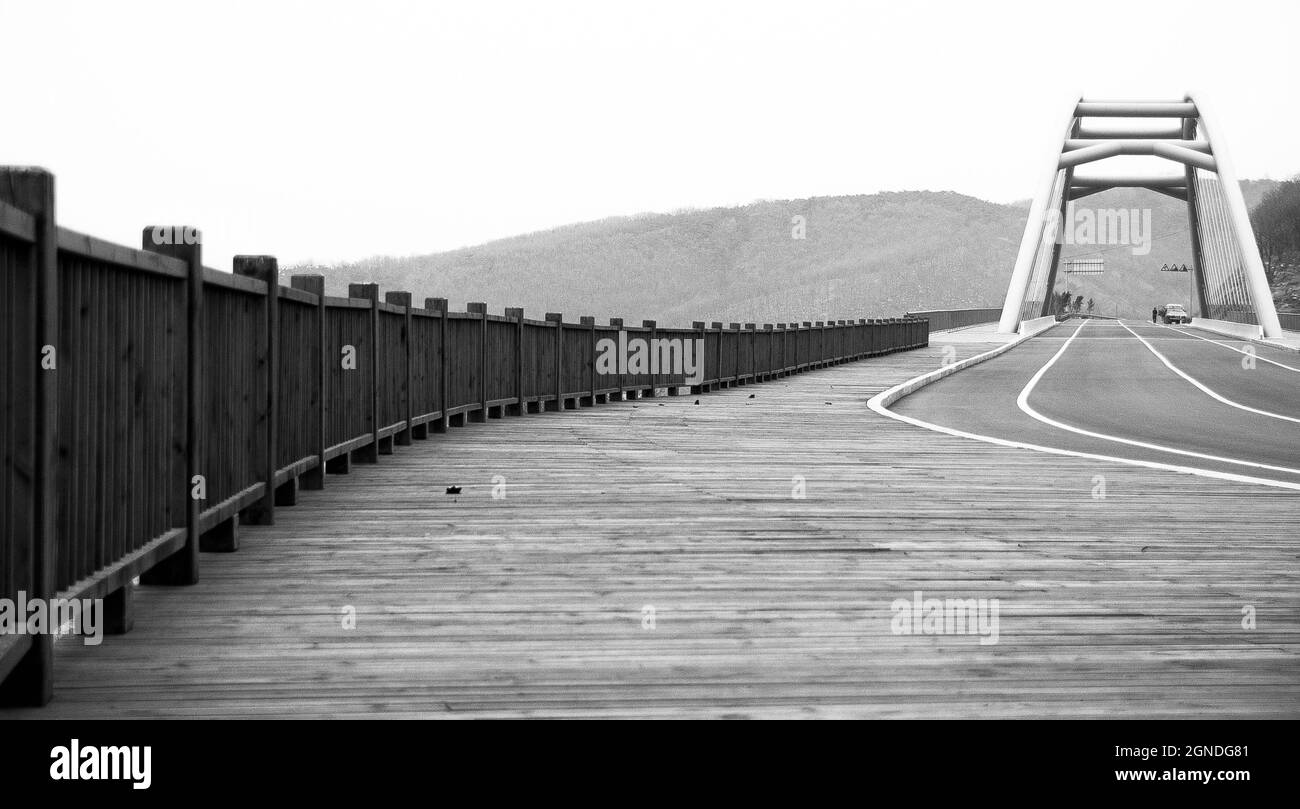 Closeup shot in black and white of a bridge with a hill background Stock Photo
