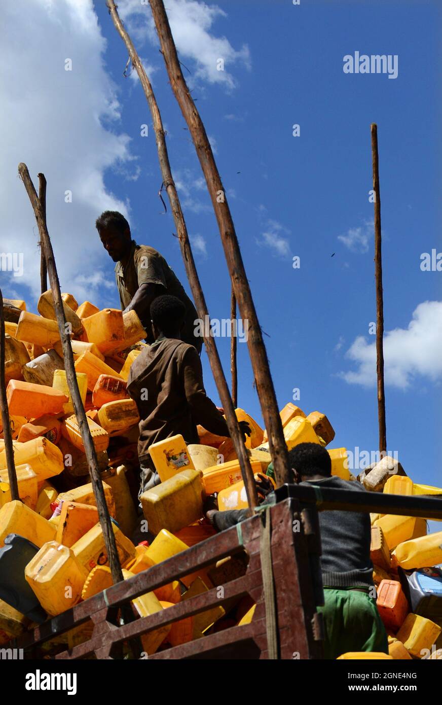 Ethiopian men loading a truck with empty yellow jerrycans. Stock Photo