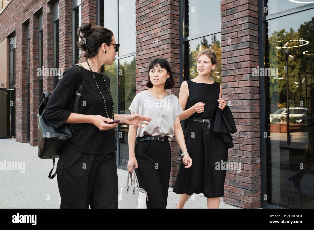Group of three stylish multi-ethnic women walking along business district sharing ideas about new project Stock Photo
