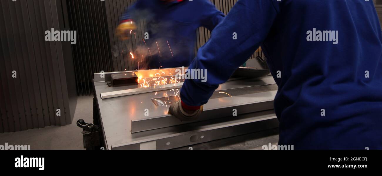Two mature men working as welders in a metal fabrication factory. Stock Photo