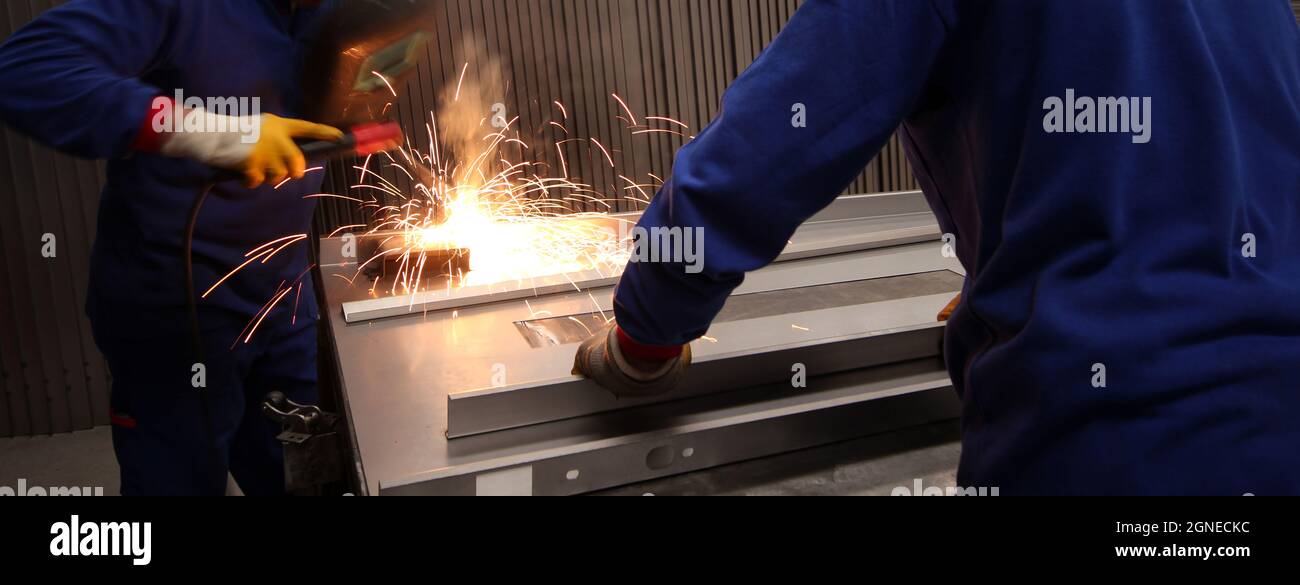 Two mature men working as welders in a metal fabrication factory. Stock Photo