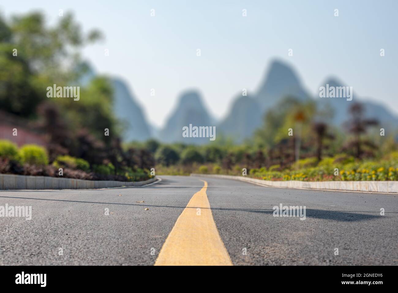 Empty road and limestone karst hills landscape with tilt-shift focus effect in Yangshuo, Guangxi province, China Stock Photo