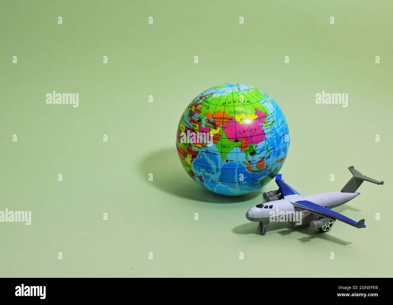 Toy plane and earth globe on green background with copy space. Selective focus. Stock Photo