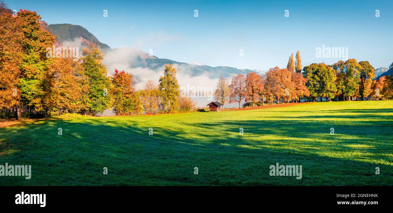 Magnificent autumn scene of Kurpark in Thumersbach village, located on the shore of the Zell lake. Colorful morning panorama of Austrian Alps, Europe. Stock Photo