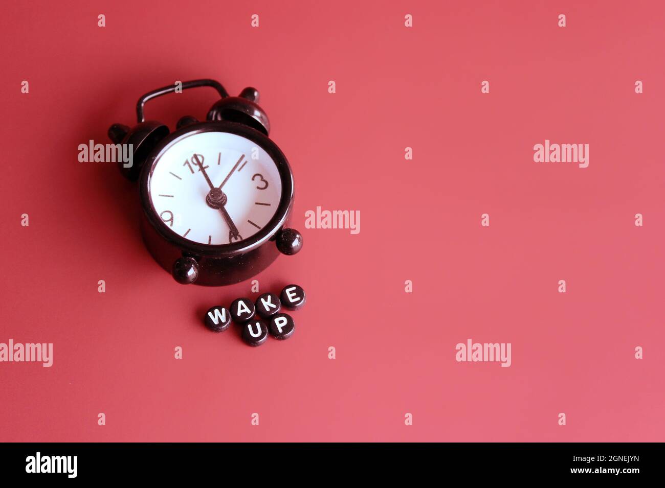 Black alarm clock and alphabet beads with text WAKE UP. Copy space for text Stock Photo