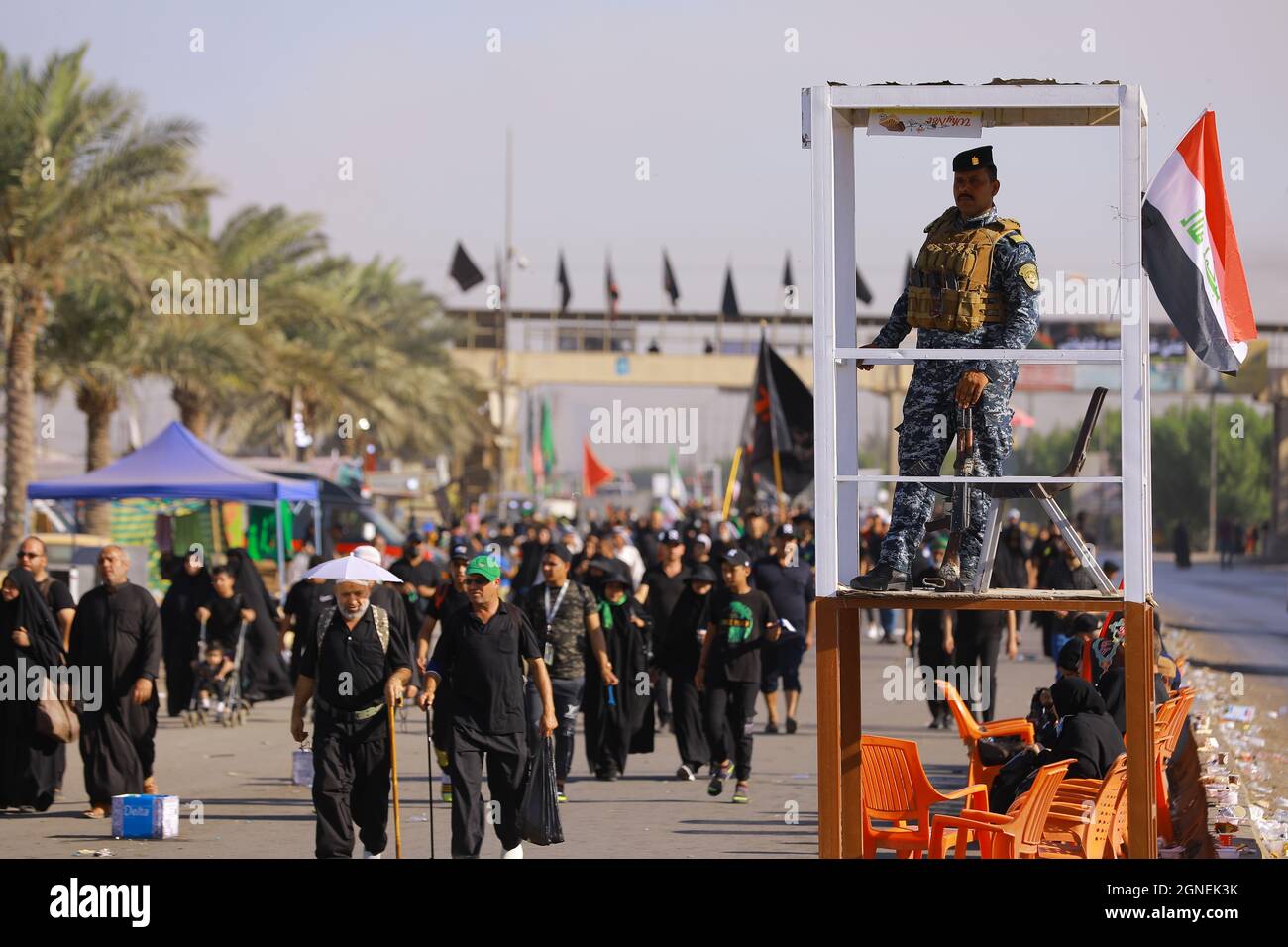 Baghdad, Iraq. 25th Sep, 2021. A member of the Iraqi security forces (R) observes Shia Muslims march from Baghdad to visit the the Husayn Mosque in Karbala on the occasion of Arba'een, also known as Chehelom, a religious observance that occurs forty days after the Day of Ashura to commemorate the martyrdom of Husayn ibn Ali, the grandson of the Islamic Prophet Muhammad, who was killed on the 10th day of the month of Muharram, according to Islamic calendar. Credit: Ameer Al Mohammedaw/dpa/Alamy Live News Stock Photo