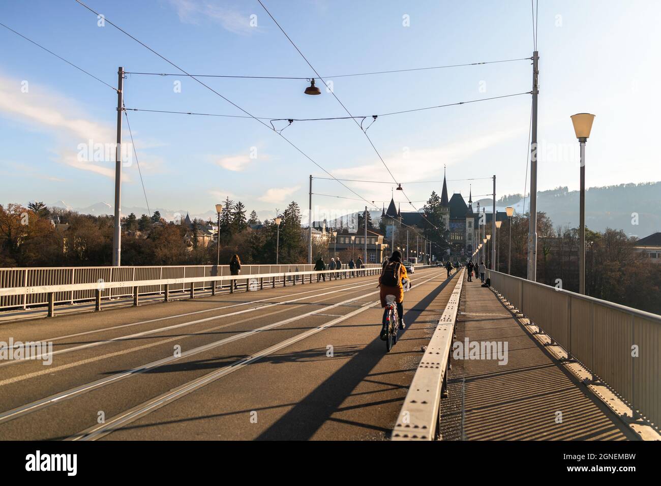 Rear view of female cycling on the bridge and Bern historical museum on background in Switzerland Stock Photo