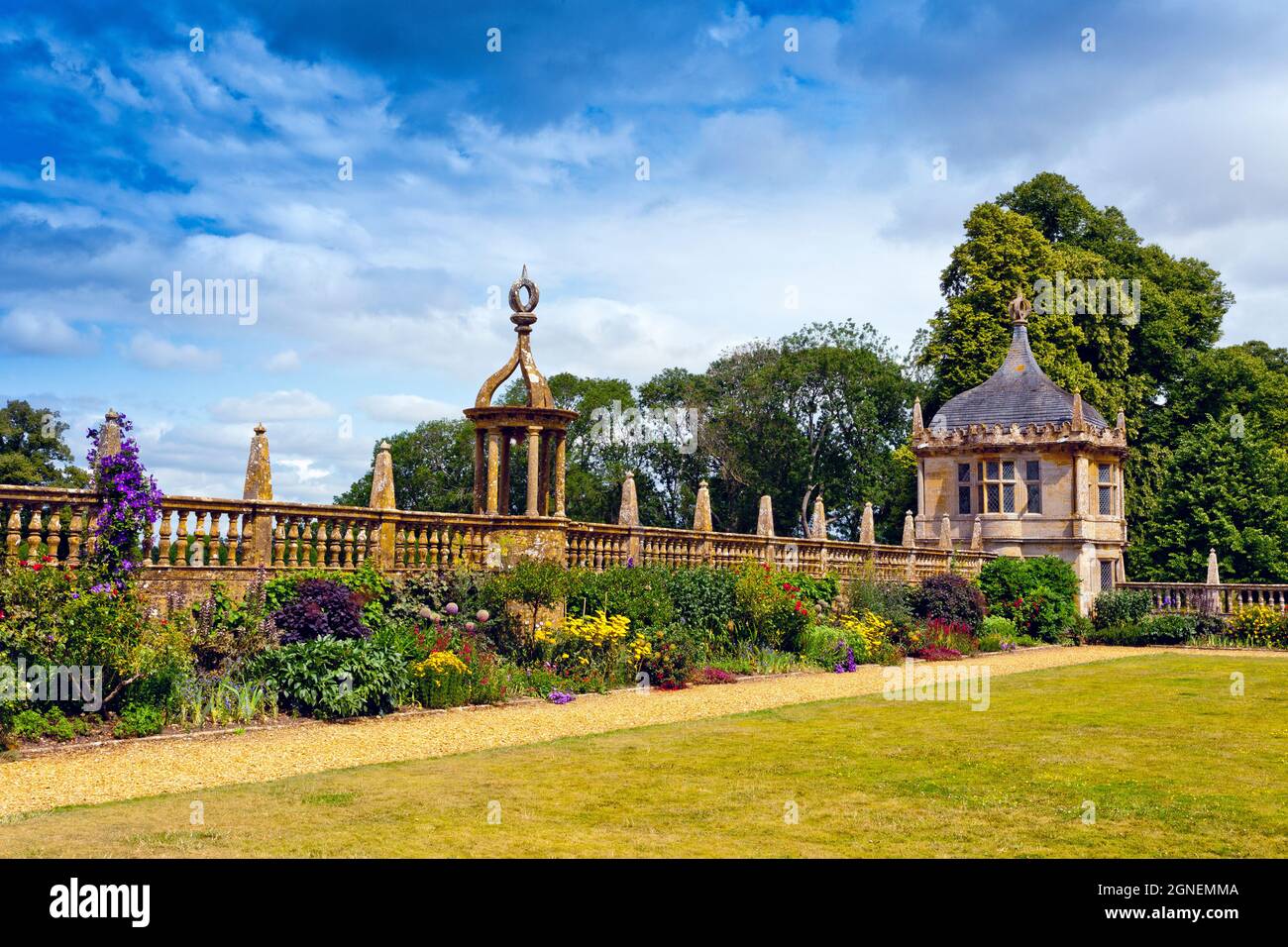 A colourful border and stone gazebo next to the east lawn at Montacute House, an Elizabethan mansion with garden near Yeovil, Somerset, England, UK Stock Photo