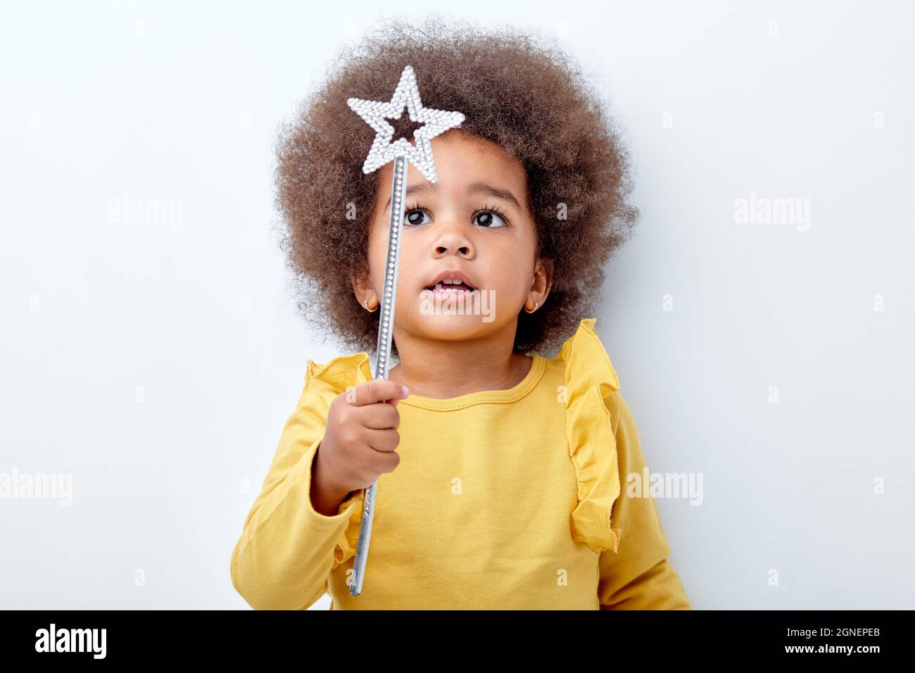 Cute african american girl wth curly fluffy hair holding magic wand, isolated on white studio