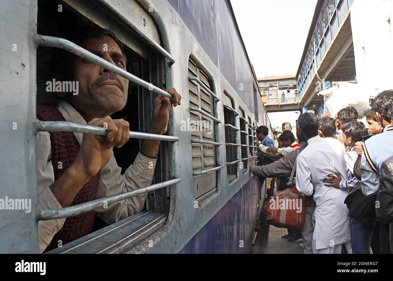 An Indian passenger peeps from the window of Indian railways 2nd class coach (ICF made) at New Delhi Railway station. Stock Photo