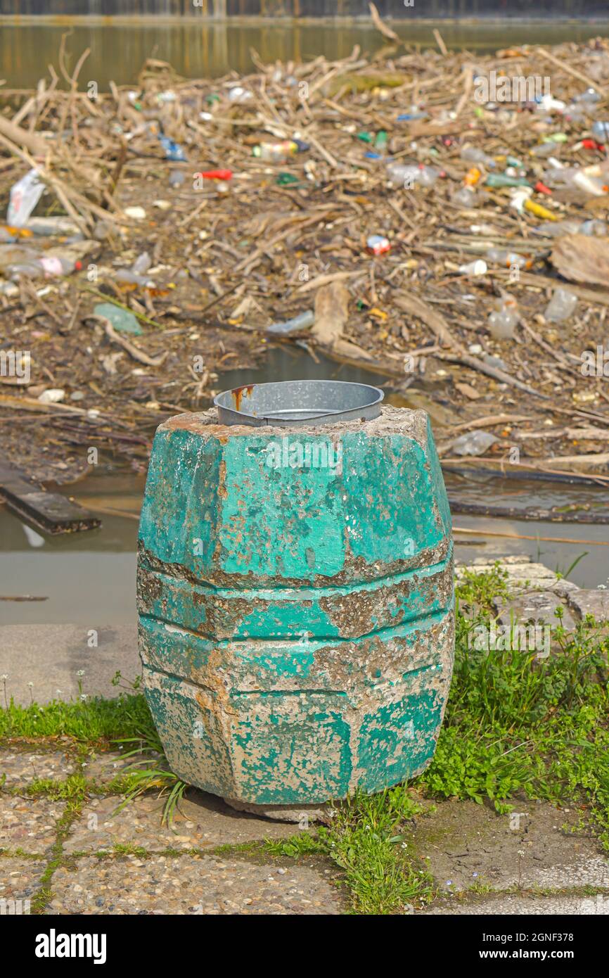 Litter bin and huge pile of floating debris in river Stock Photo