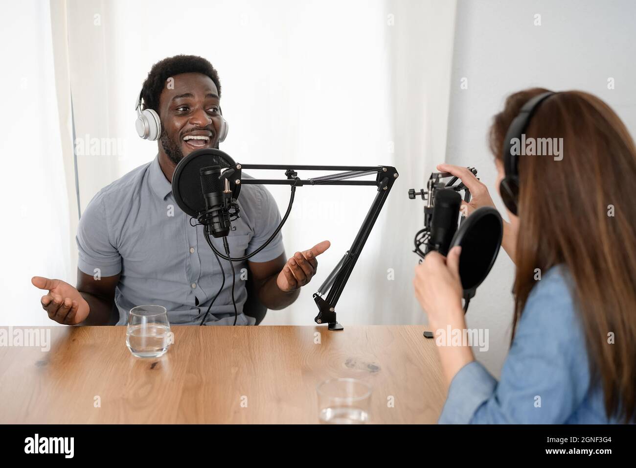 Multiracial people recording a podcast using microphone and headphones from home studio Stock Photo