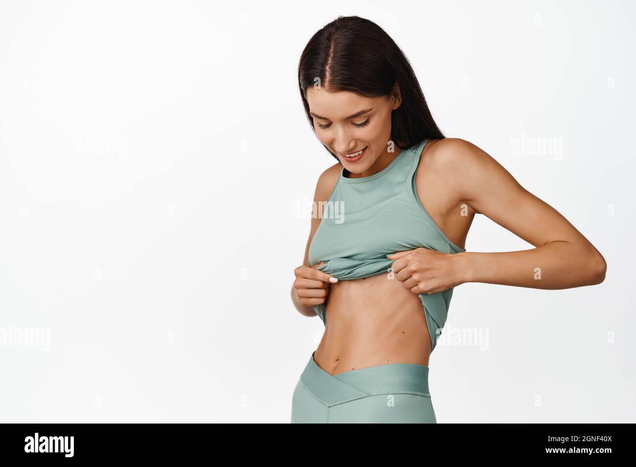 Fitness girl shows her abs, lift t-shirt and looking at slim fit belly,  smiling pleased after workout. Concept of sport and healthy lifestyle Stock  Photo - Alamy