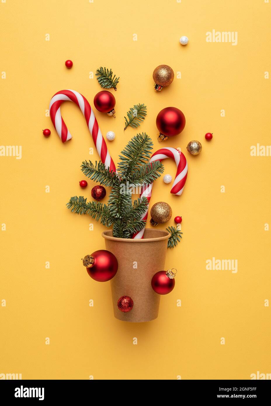Christmas card with candy cane, Christmas balls, and fir tree branches on yellow background Stock Photo