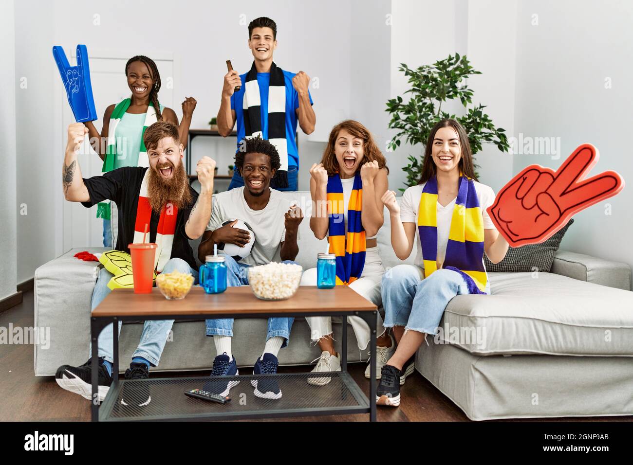 Group of friends supporting football team watching tv al home sitting ...