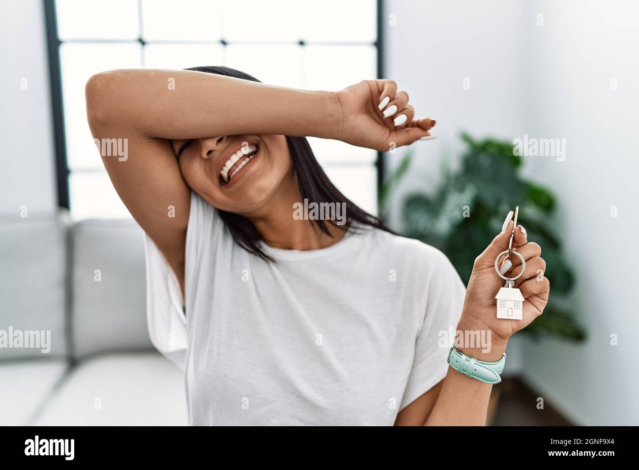 Young hispanic woman holding keys of new home smiling cheerful playing ...