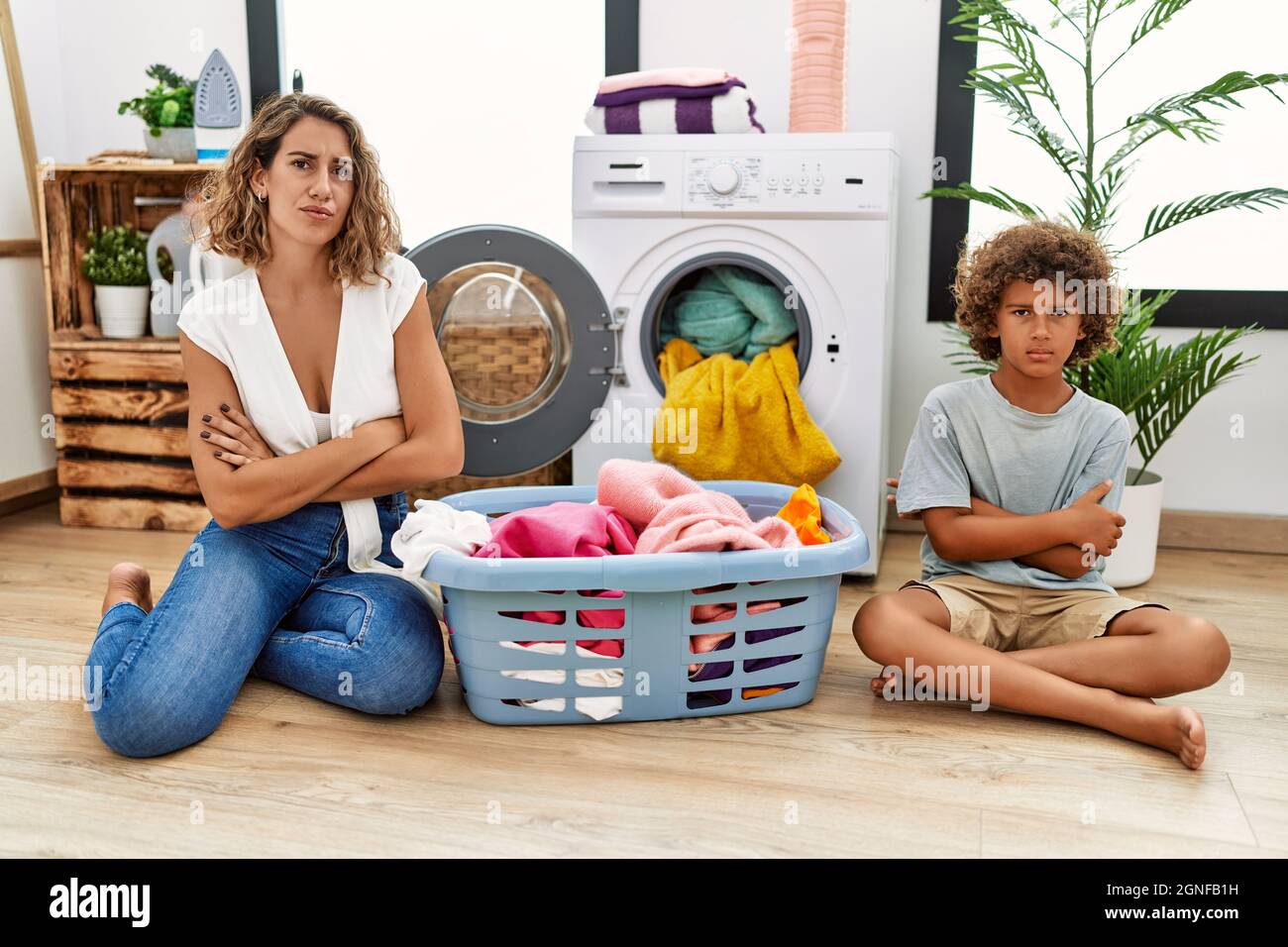 Young woman and son putting dirty laundry into washing machine skeptic ...