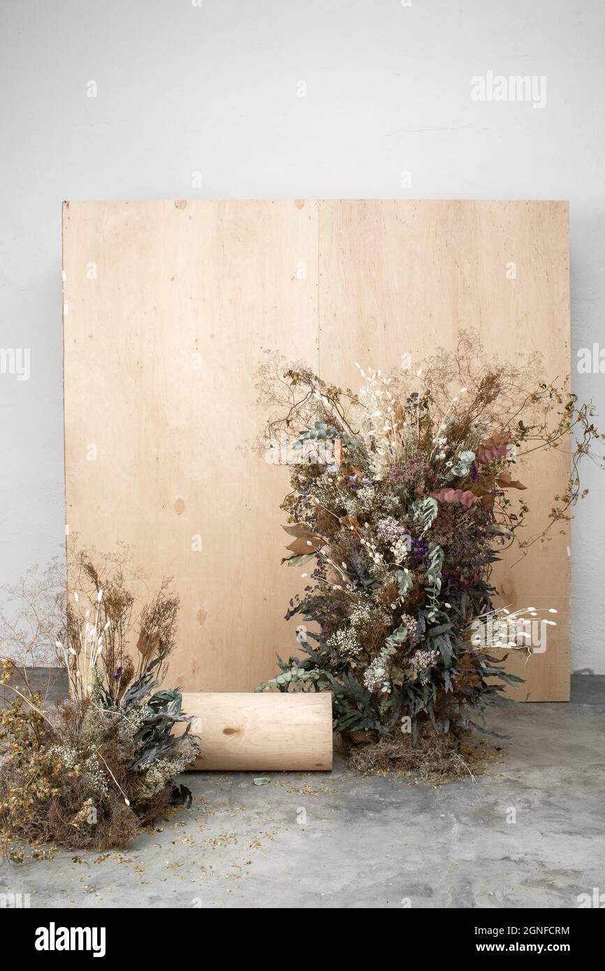Large floral arrangement bouquet of dried flowers on the background of a wood wall and cement floor. The concept of inspiration, congratulations, autu Stock Photo