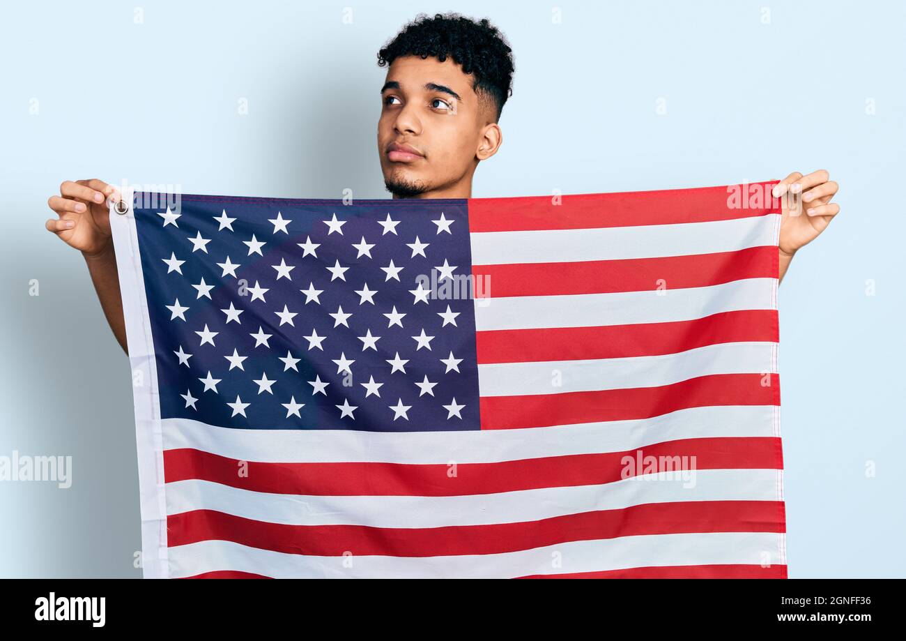 Young african american man holding united states flag smiling looking ...