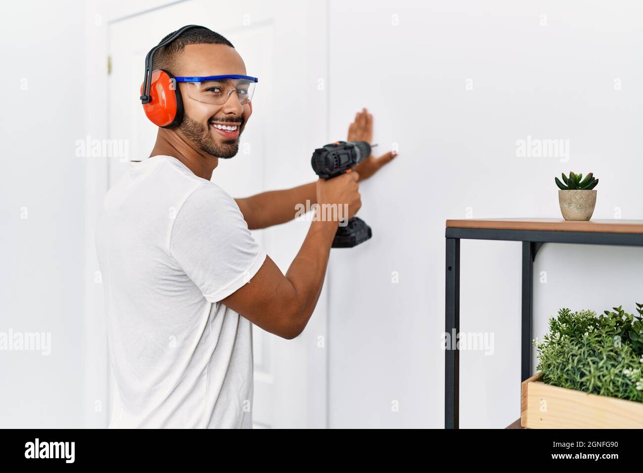 Young hispanic man smiling confident using drill at home Stock Photo