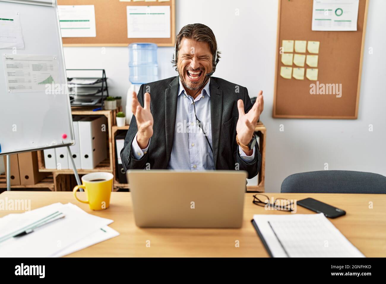 Handsome middle age man wearing call center agent headset at the office  celebrating mad and crazy for success with arms raised and closed eyes  screami Stock Photo - Alamy
