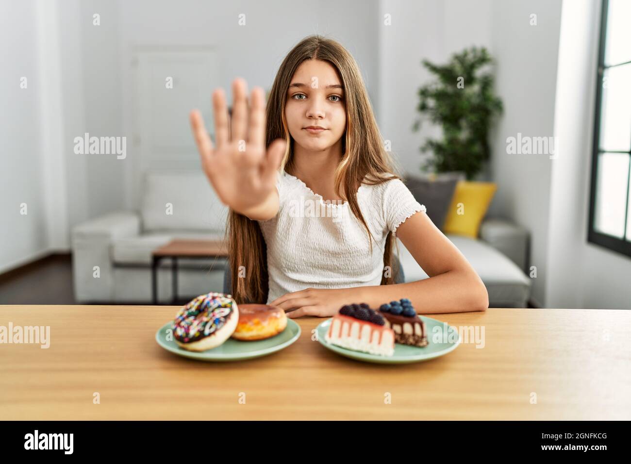 Young teenager eating cakes and sweets with open hand doing