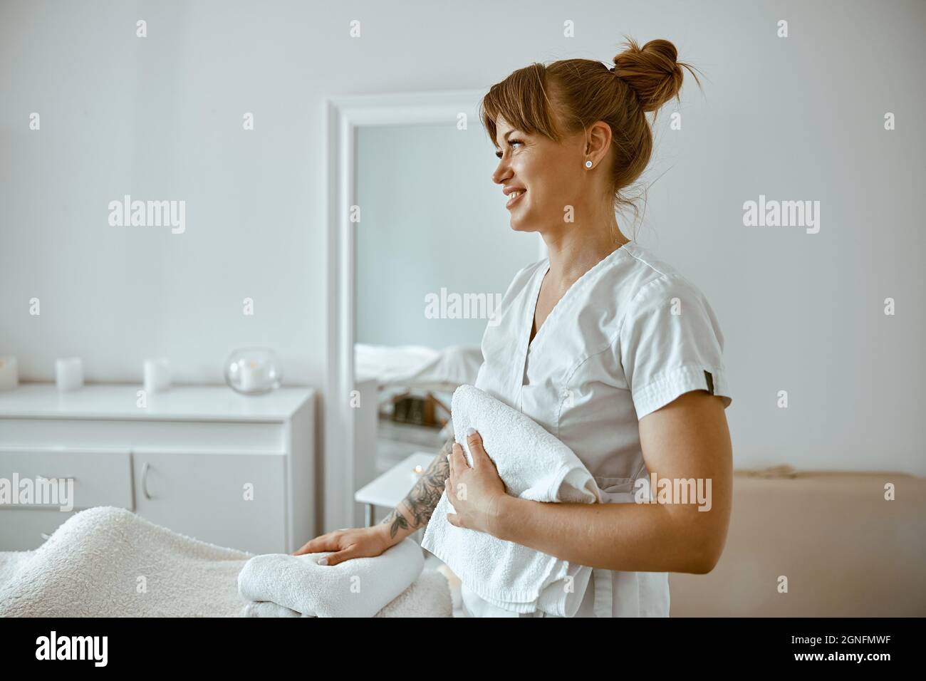 beautiful happy caucasian female masseur is posing in white minimalistic modern treatment salon Stock Photo