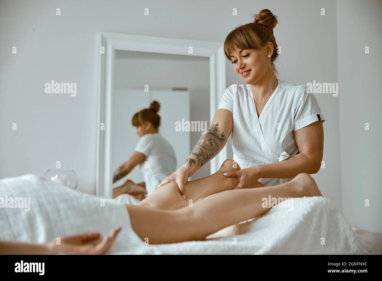 Professional caucasian specialist is doing leg message at modern ...