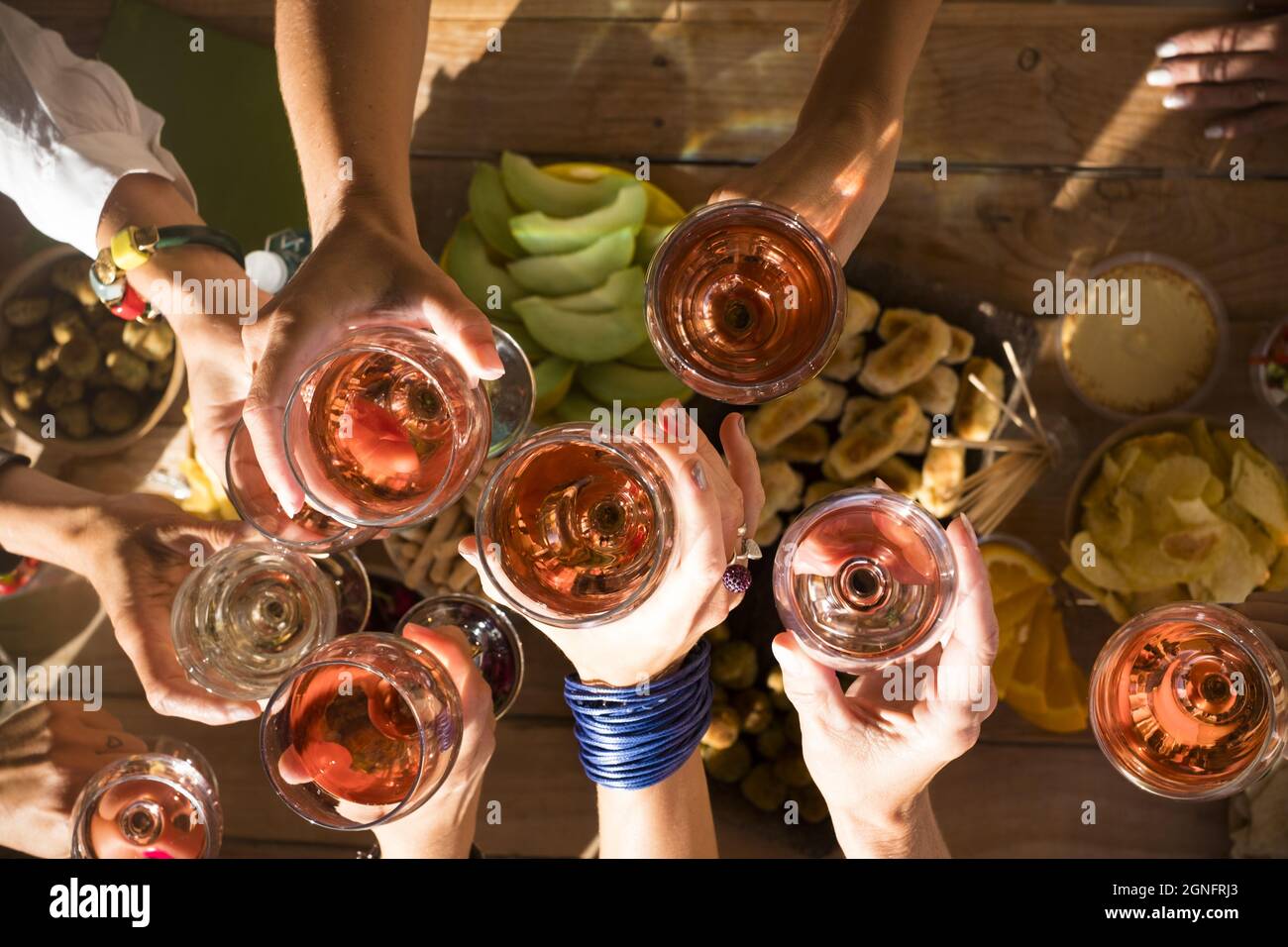 Top view of group of women hands toasting together with glasses of wine. Friends celebrating at restaurant. Top view of friends raising hands and toas Stock Photo