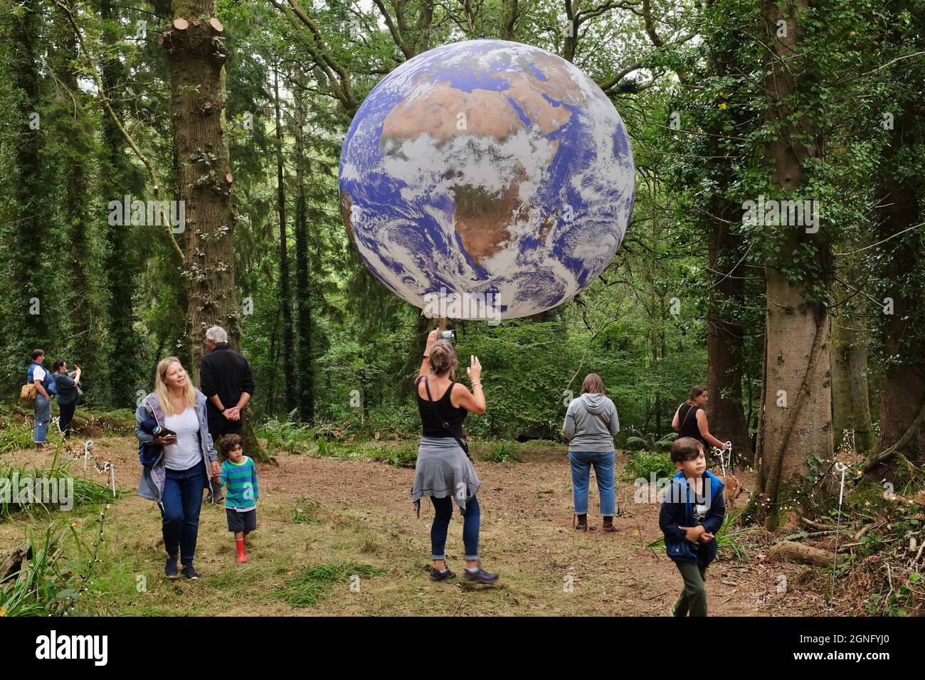 Gaia Artwork, Symondsbury, Dorset, UK. 25th Sep, 2021. Visitors contemplate a representation of the earth suspended in woodland in Symondsbury Dorset. Measuring seven metres in diameter, Artist Luke Jerram's Gaia features 120dpi detailed NASA imagery of the Earth's surface and provides visitors the opportunity to see our planet like never before. Credit: Tom Corban/Alamy Live News Stock Photo