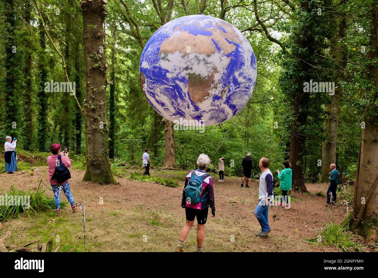 Gaia Artwork, Symondsbury, Dorset, UK. 25th Sep, 2021. Visitors contemplate a representation of the earth suspended in woodland in Symondsbury Dorset. Measuring seven metres in diameter, Artist Luke Jerram's Gaia features 120dpi detailed NASA imagery of the Earth's surface and provides visitors the opportunity to see our planet like never before. Credit: Tom Corban/Alamy Live News Stock Photo