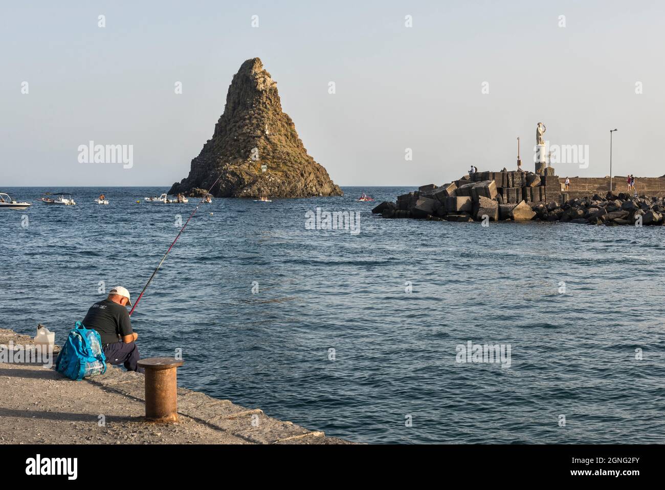 The harbour of Aci Trezza, Sicily, with the basalt sea stack of Faraglione Grande, one of the Faraglioni or Isole dei Ciclopi (Cyclopean Islands) Stock Photo