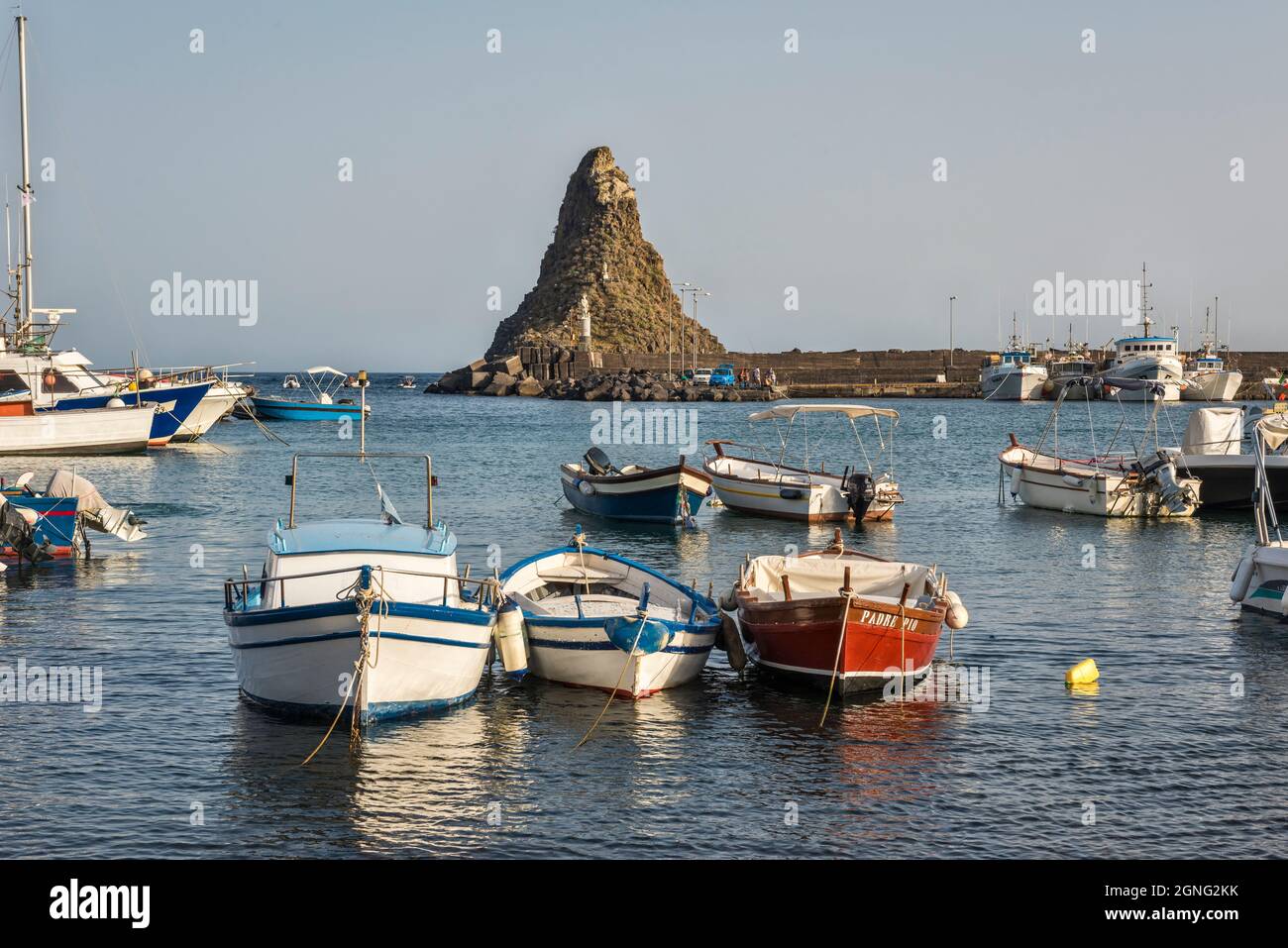 The harbour of Aci Trezza, Sicily, with the basalt sea stack of Faraglione Grande, one of the Faraglioni or Isole dei Ciclopi (Cyclopean Islands) Stock Photo