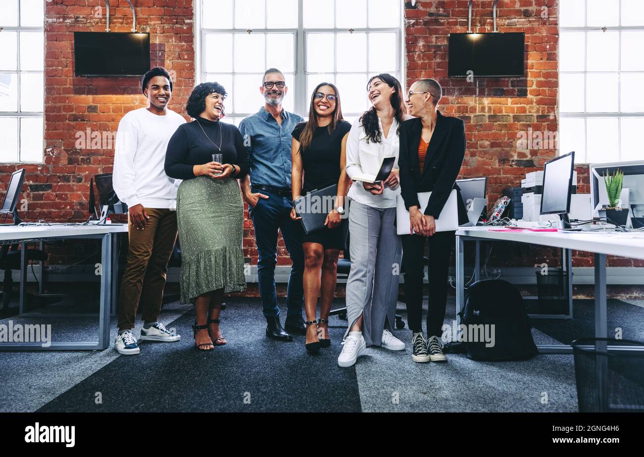 Happy group of businesspeople laughing cheerfully in a modern workplace ...